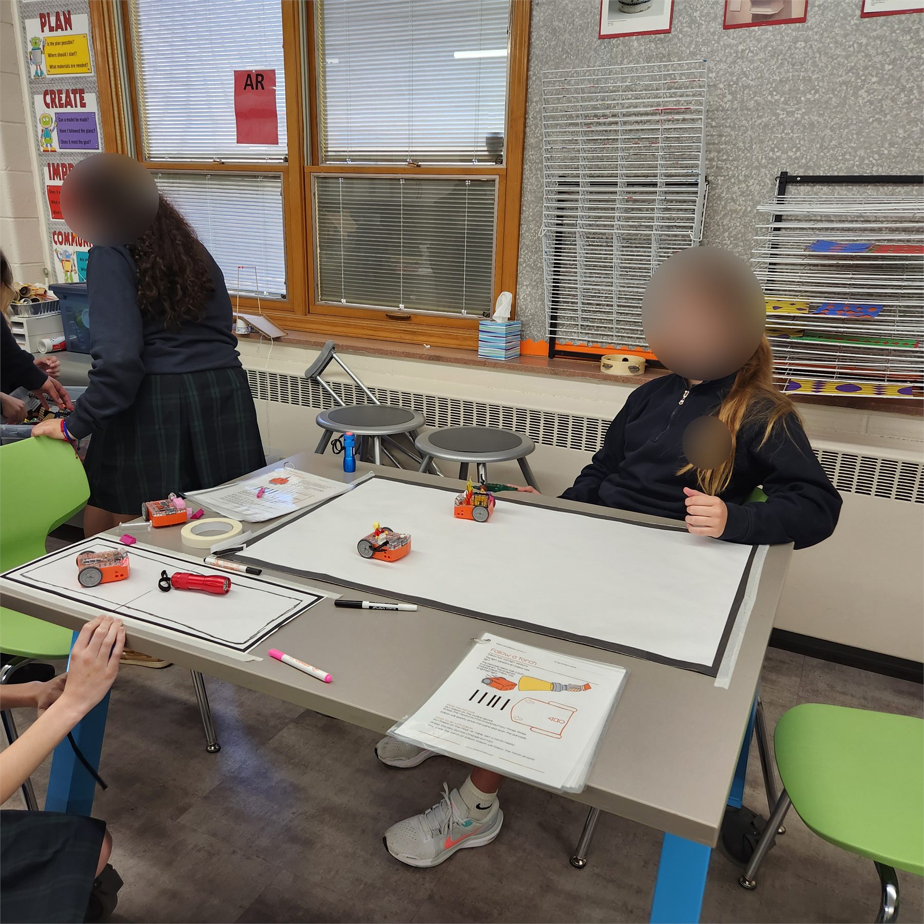 Students testing Edison robots on a whiteboard track