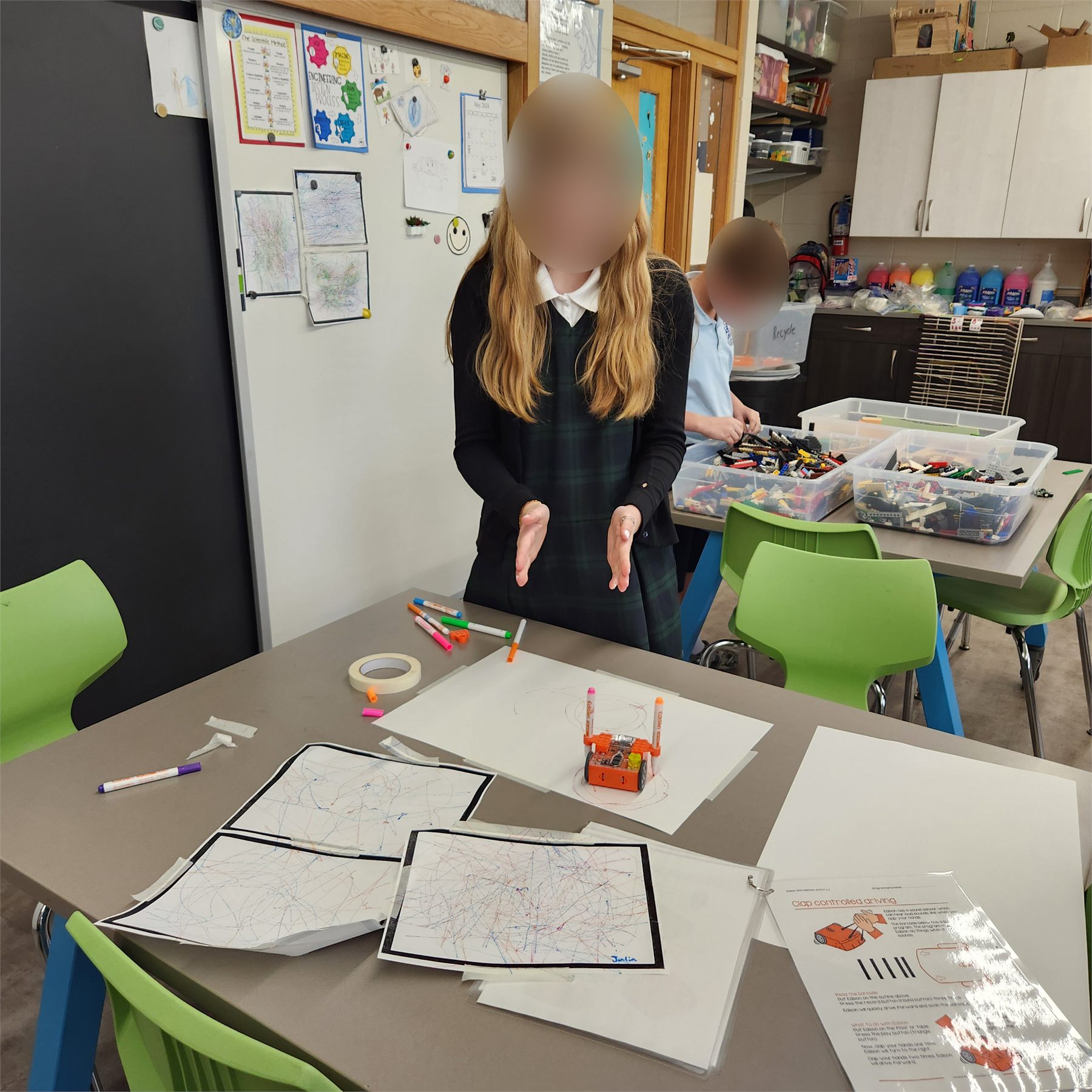 Student watching an Edison robot drawing with markers