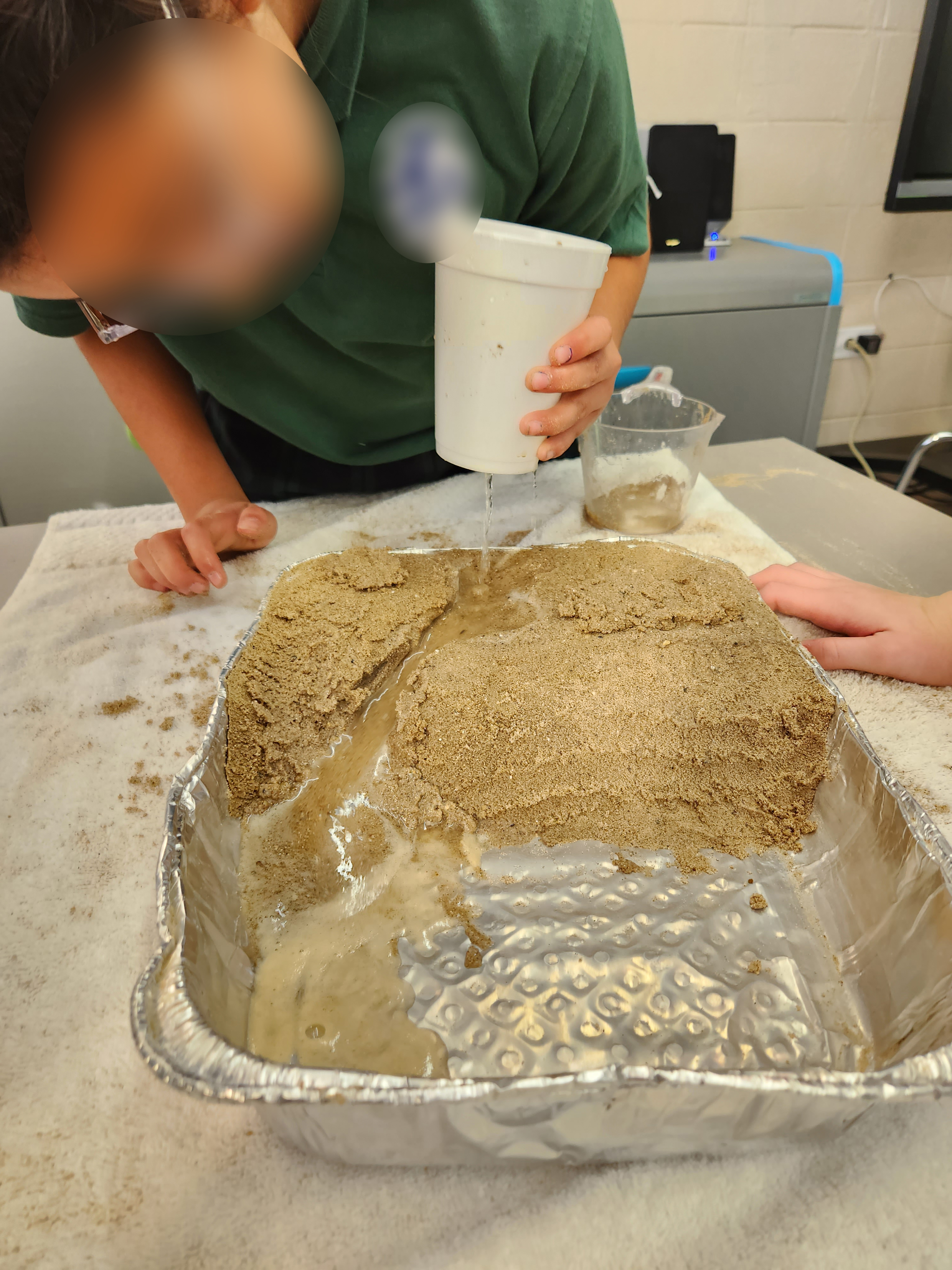 Student water erosion investigation using sand and flowing water