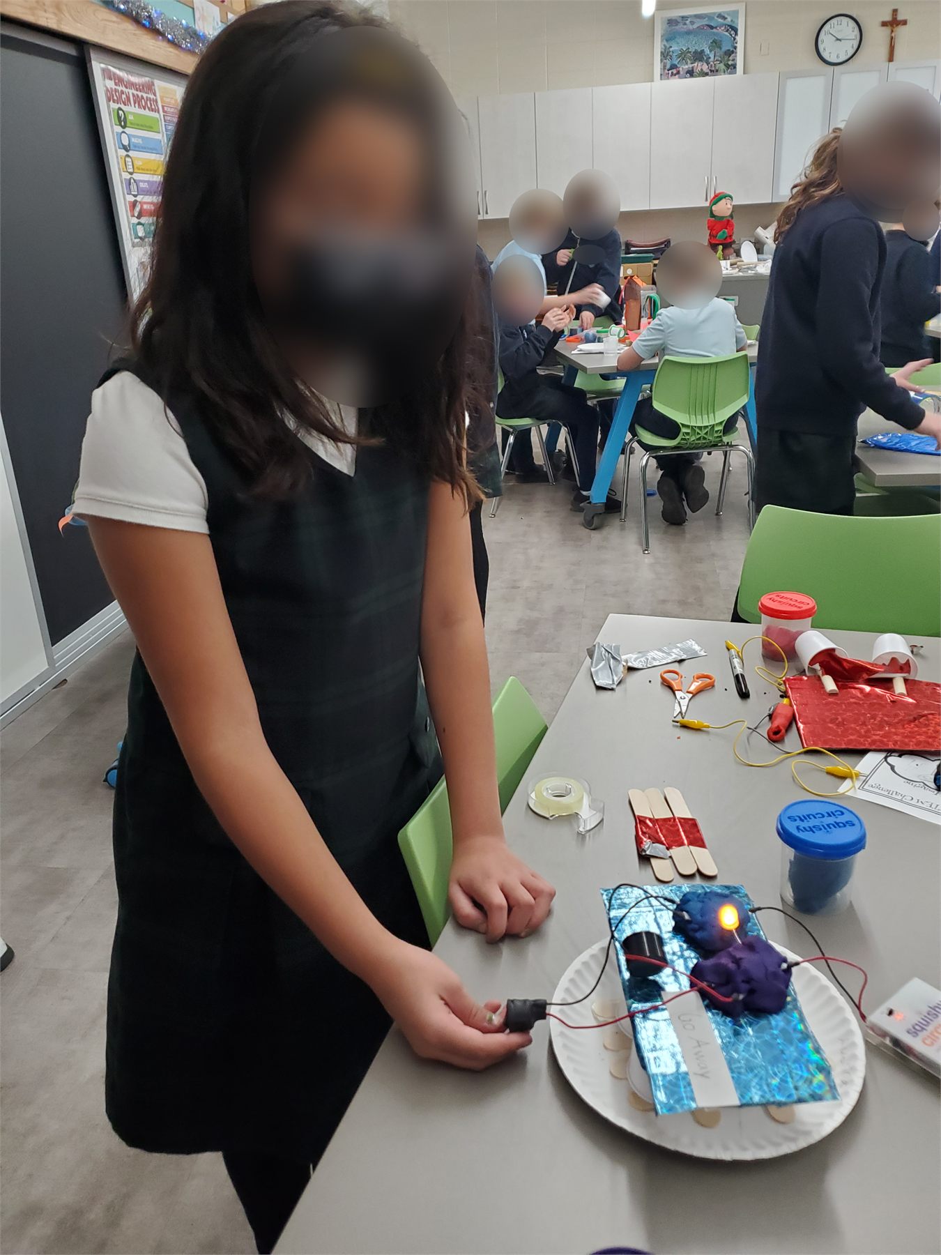 Student showing a squishy circuits emergency sign